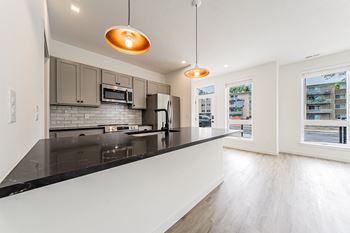 A modern kitchen with a black countertop and stainless steel appliances.
